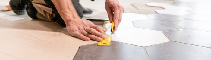 Male,Worker,Makes,Measurements,And,Installing,New,Wooden,Laminate,Flooring.